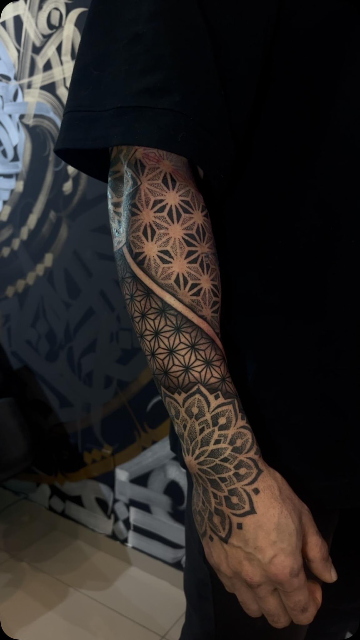 Tatuagem geométrica com padrões repetidos e mandala do braço até a mão