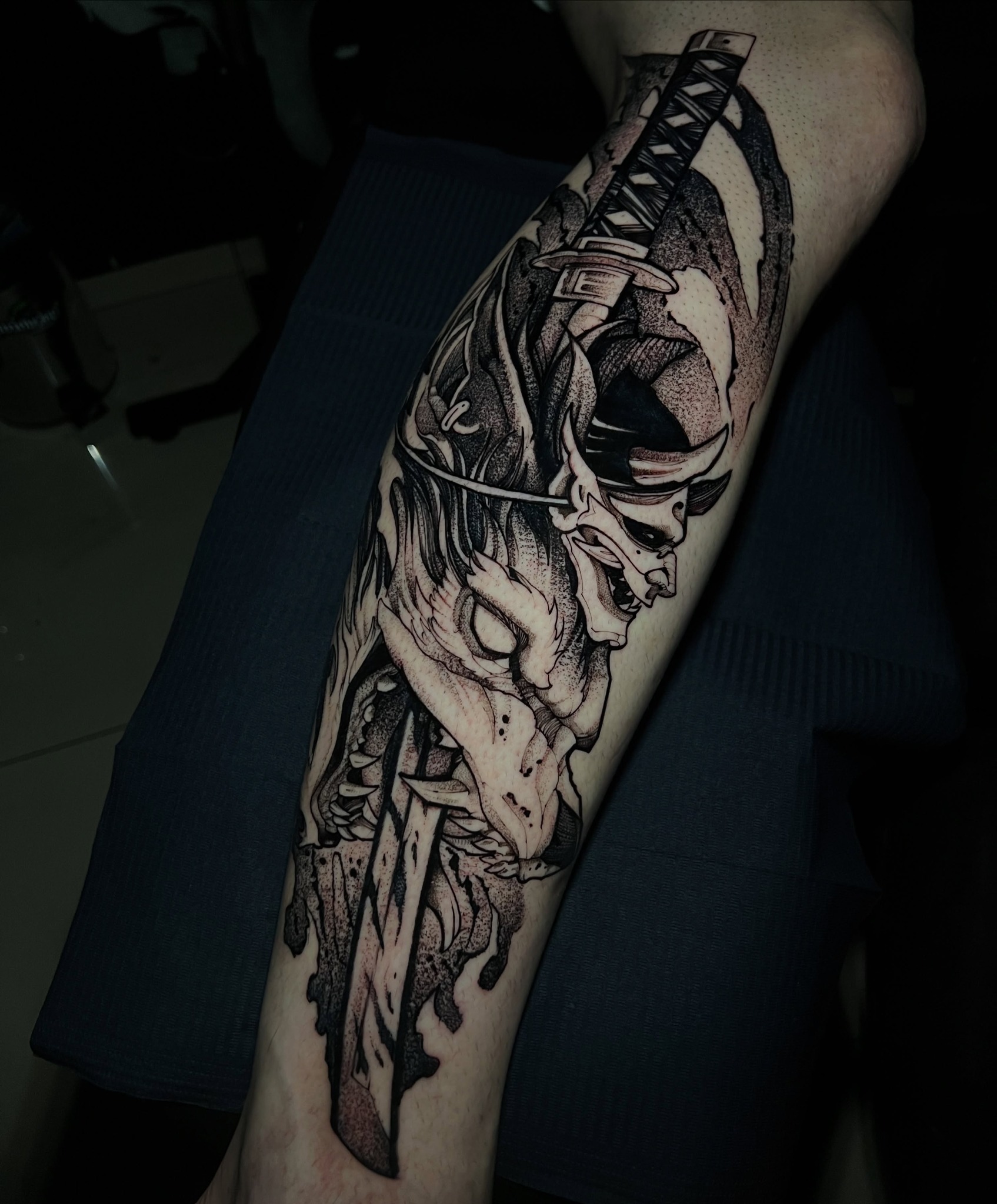 Tatuagem em blackwork de máscara e espada no antebraço