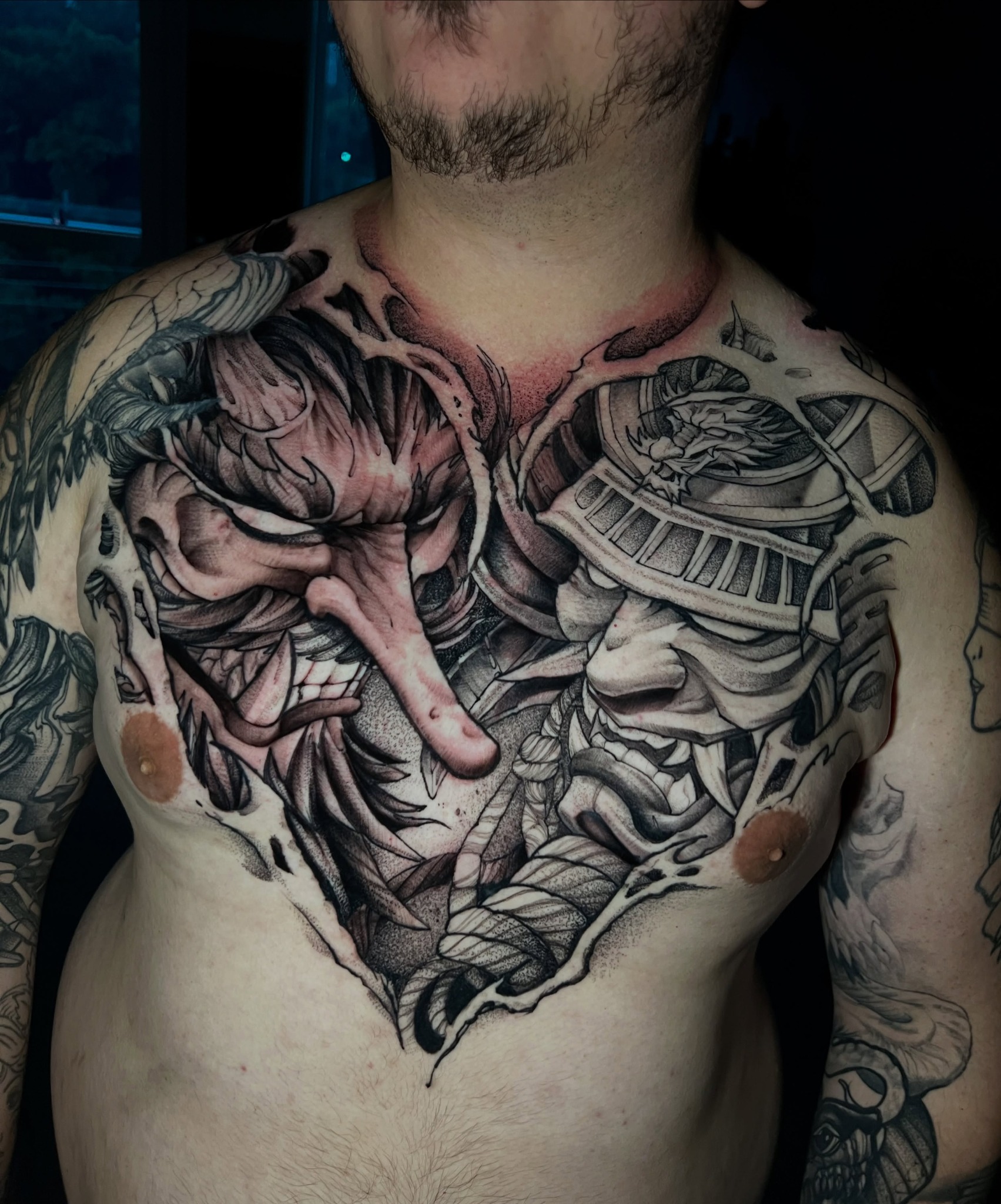 Duas máscaras orientais em uma composição de tatuagem no peito